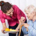 A support worker feeding an elderly woman in a wheelchair