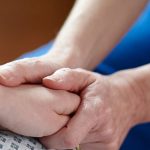 A support worker holding a patient's hand
