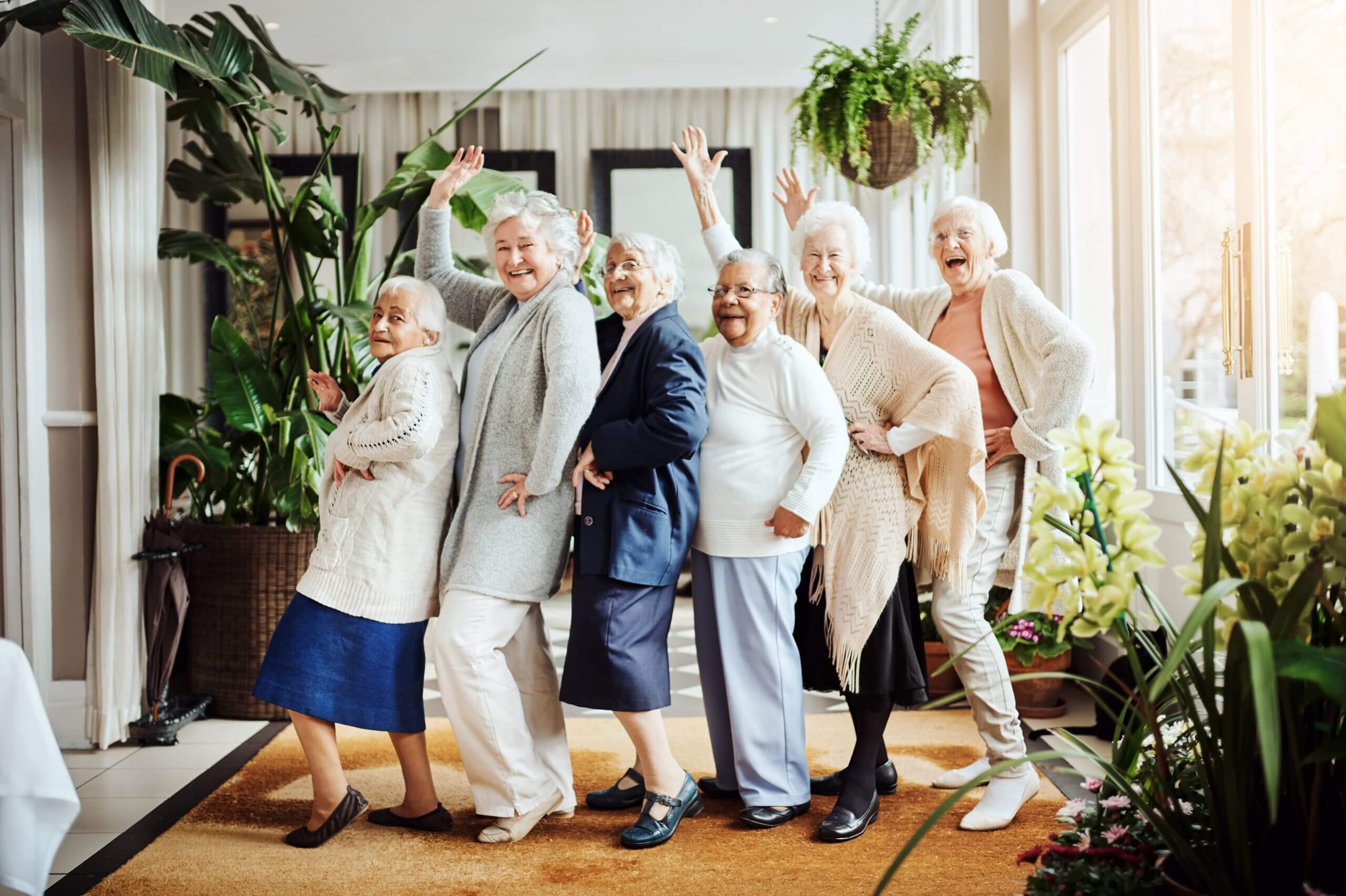 A group of elderly women waving and smiling at the camera