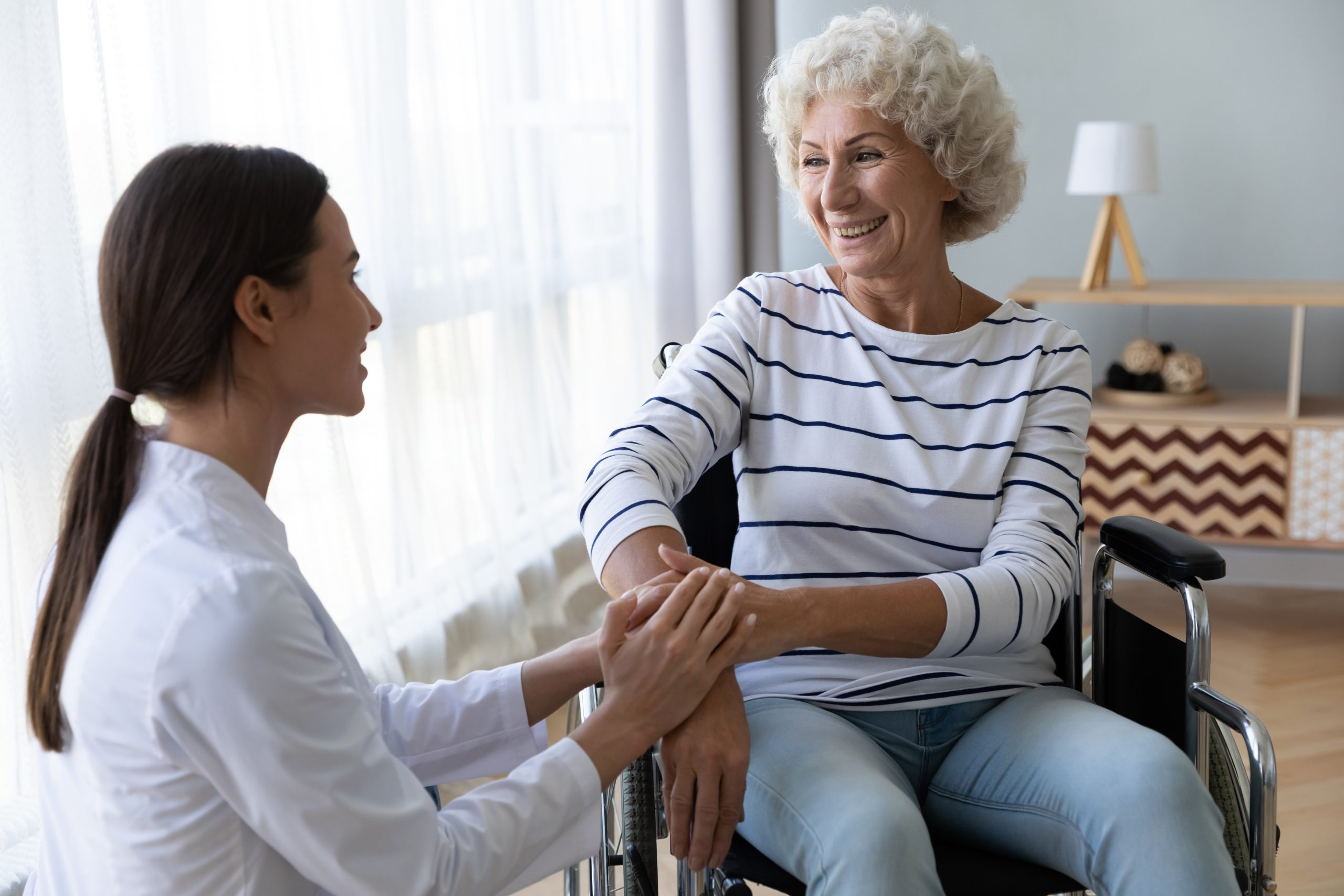 A support worker talking to an elderly woman in a wheelchair