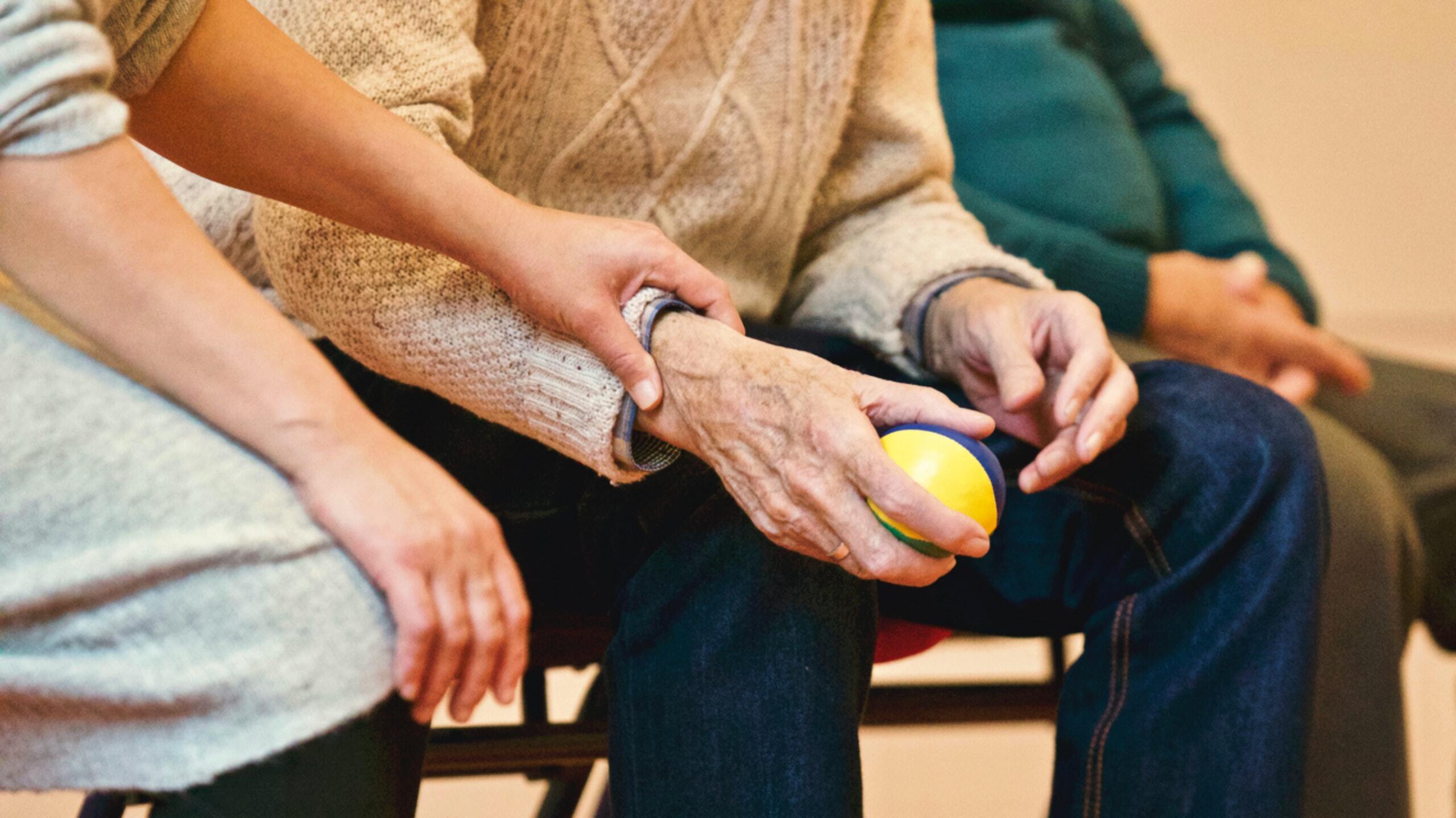 3 people sitting down with the center person holding a ball