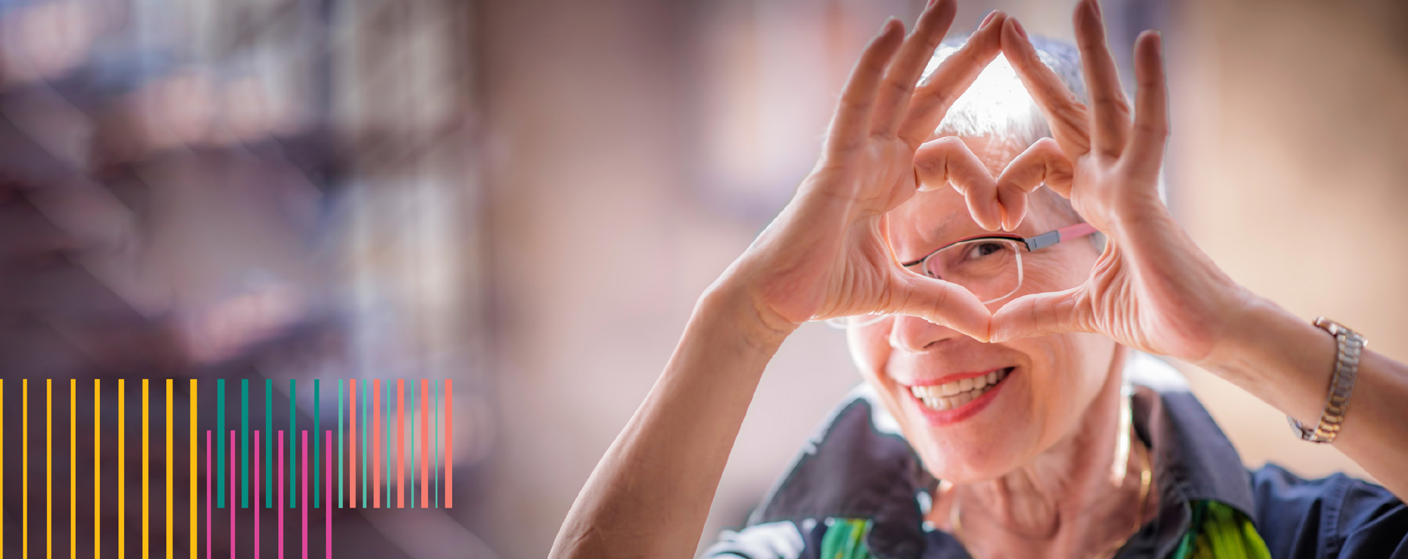 An elderly woman forming a heart with her fingers