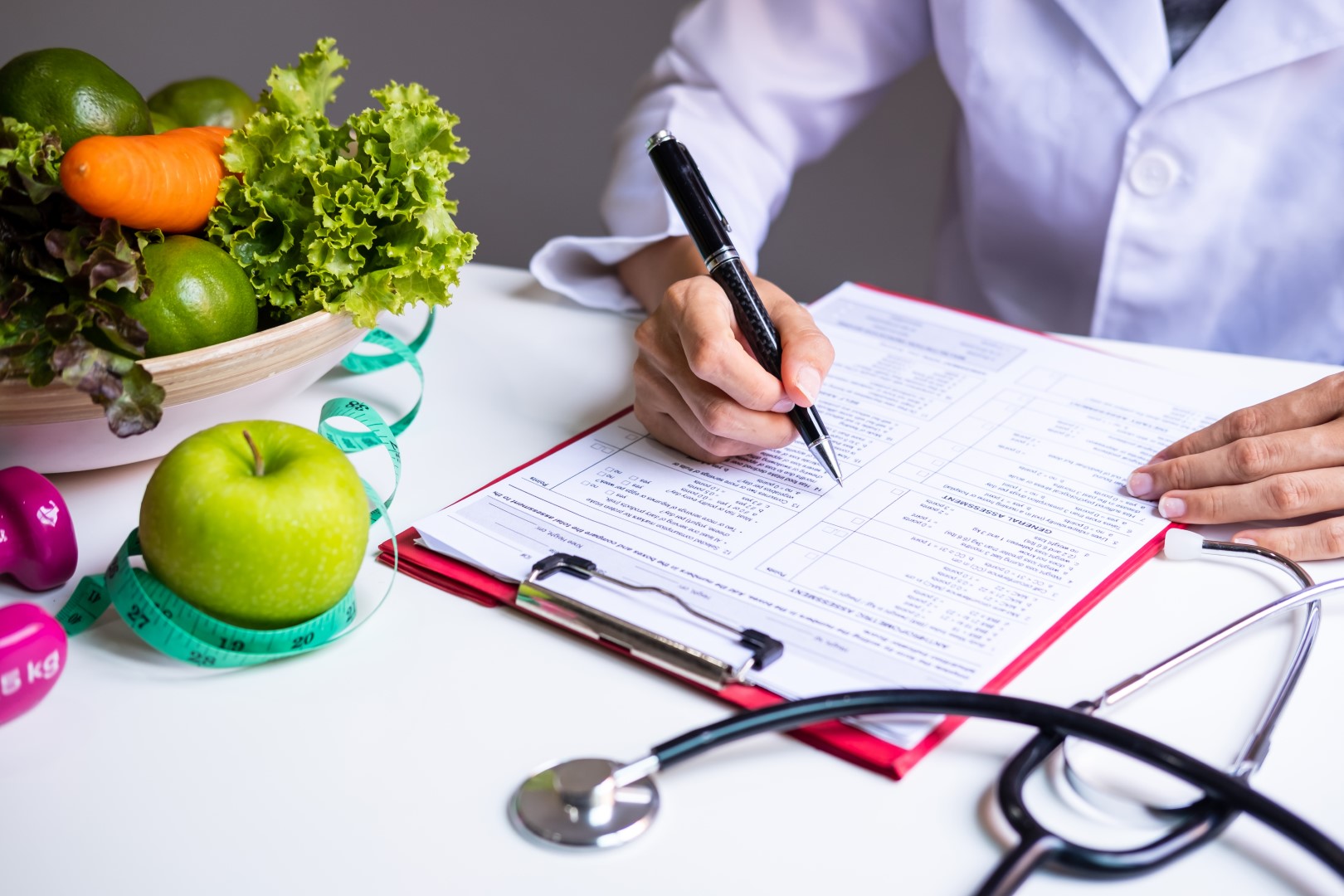 A Dietitian doing paperwork with fruits and vegetables on the top left corner