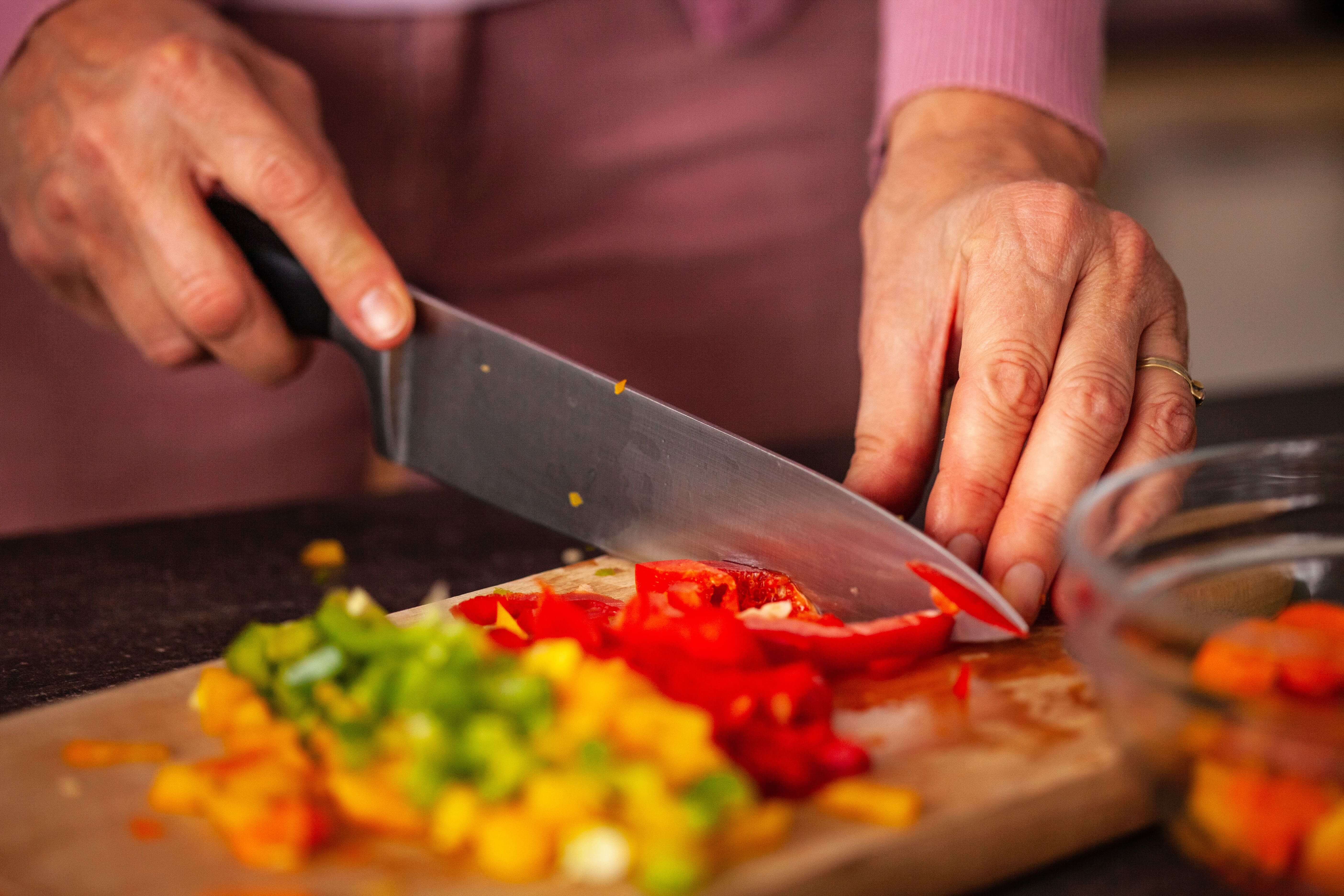 An elderly person slicing tomatoes