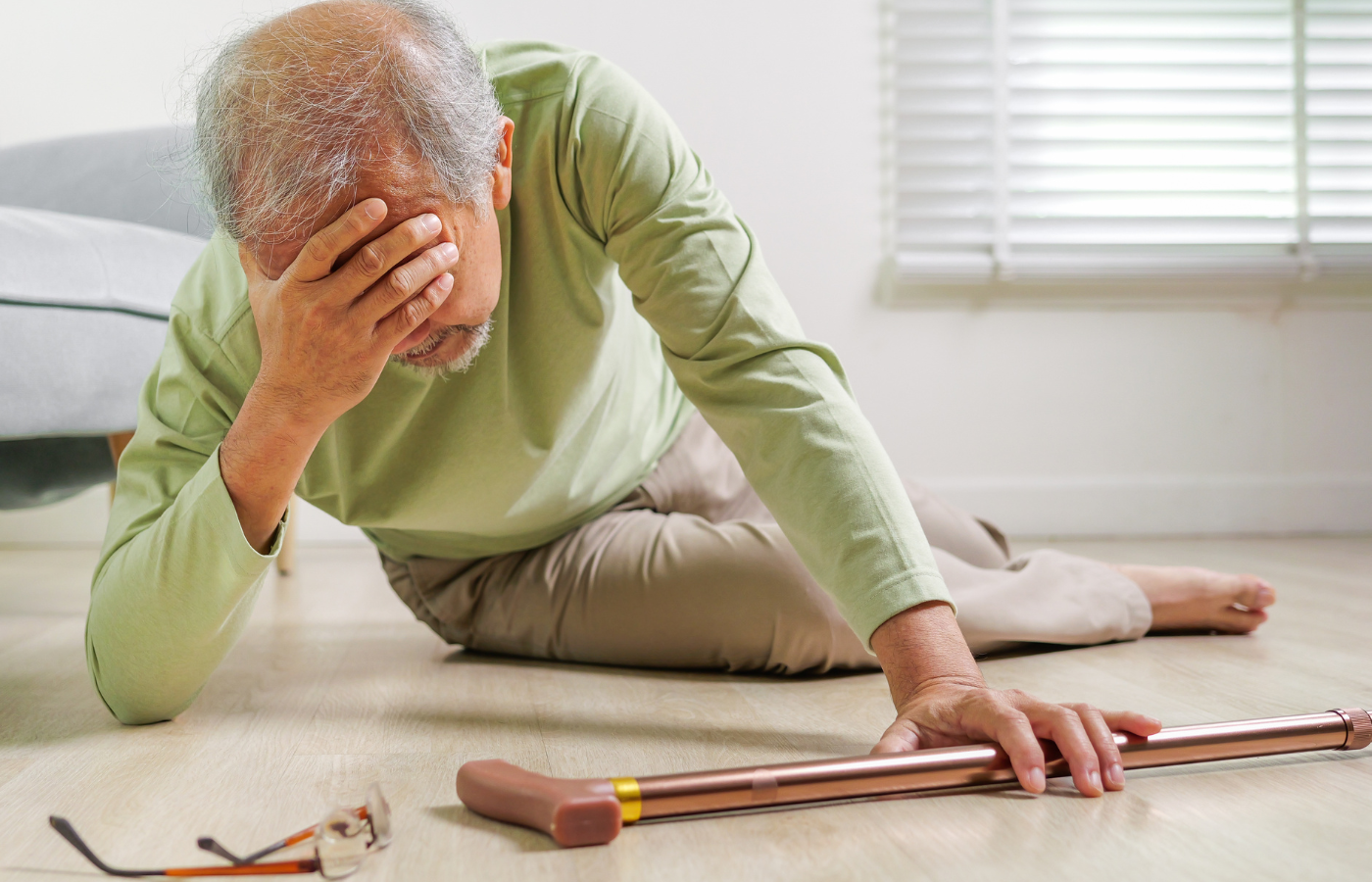An elderly man on the floor, holding his head after a fall