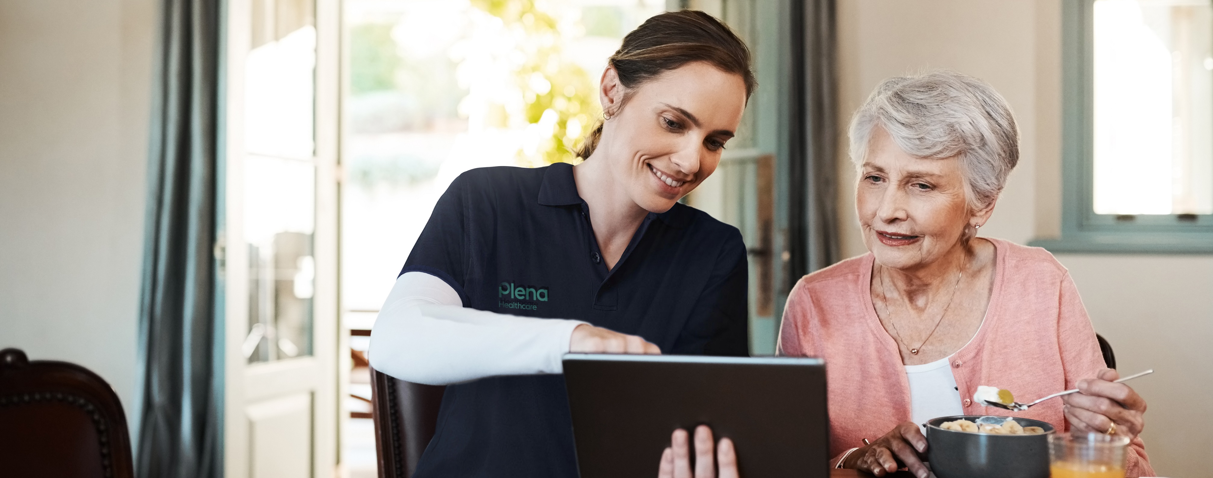 A Plena Dietitian and elderly woman looking at a tablet